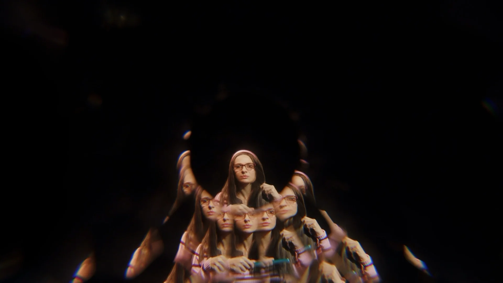 Video art still — a face multiplied into a kaleidoscopic trail against black